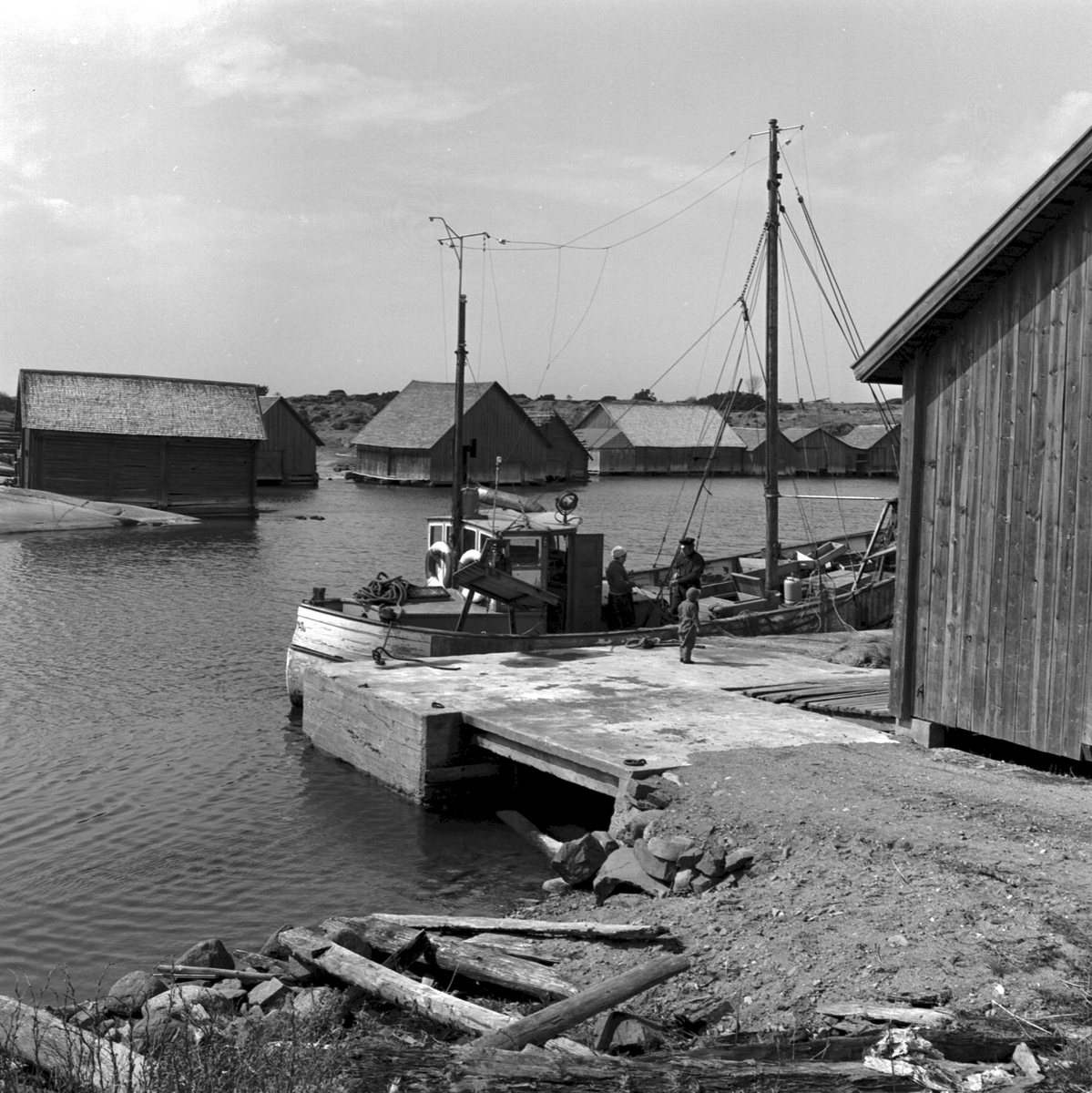 Ålandsresa. Skärgård. Fiskeläger med fiskebåt, Suomi 45 och fiskare som iordningställer näten