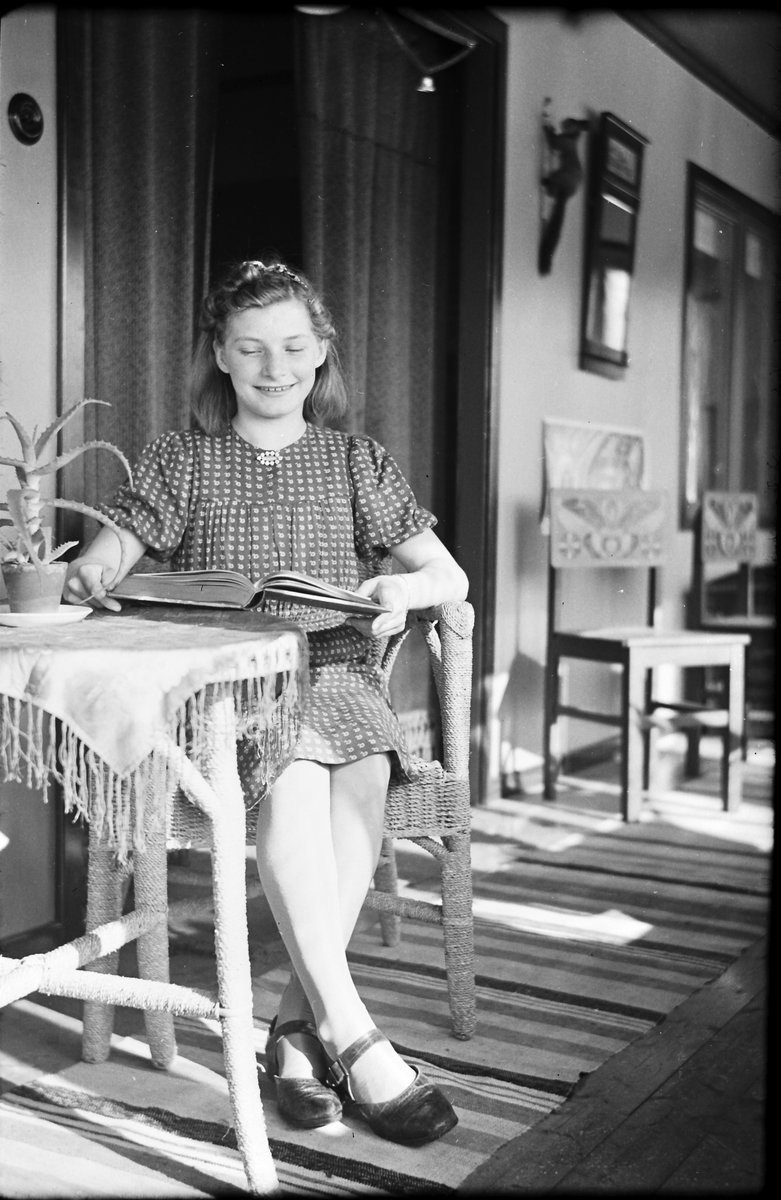 Flickan Ella Lundgren sitter vid ett bord och tittar i en bok. På bordet står en kaktus och i bakgrunden hänger en uppstoppad ekorre på väggen över stolar med kurbitsliknande dekor.