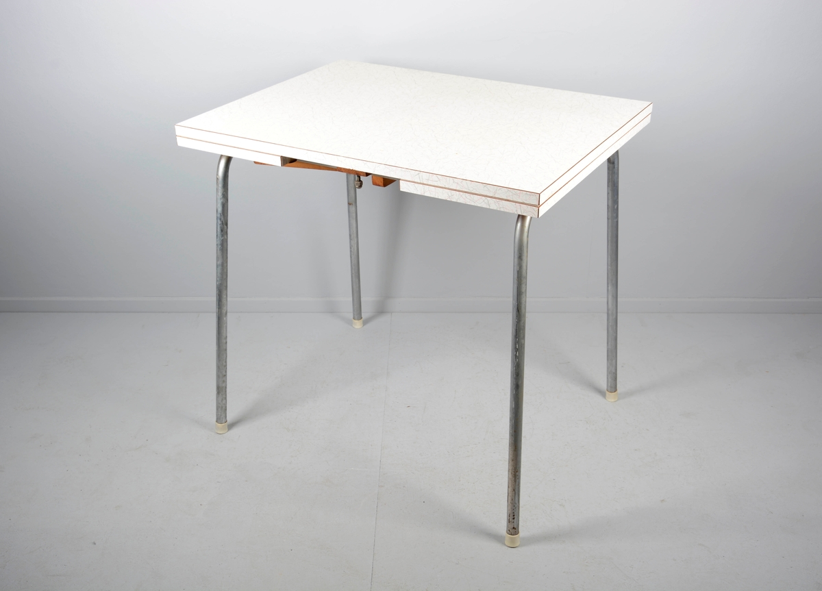 Rektangulært kjøkkenbord med to uttrekkbare sideklaffer. 4 lett skråstilte stålrørsben med plastbeskyttere nederst. Bordplate i respatex