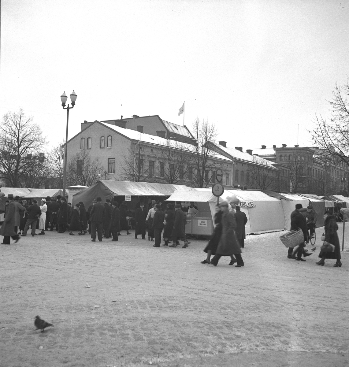 Hindersmässan i Örebro den 28 januari 1937. Marknadsstånd på Stortorgets östra del med människor spatserande framför.