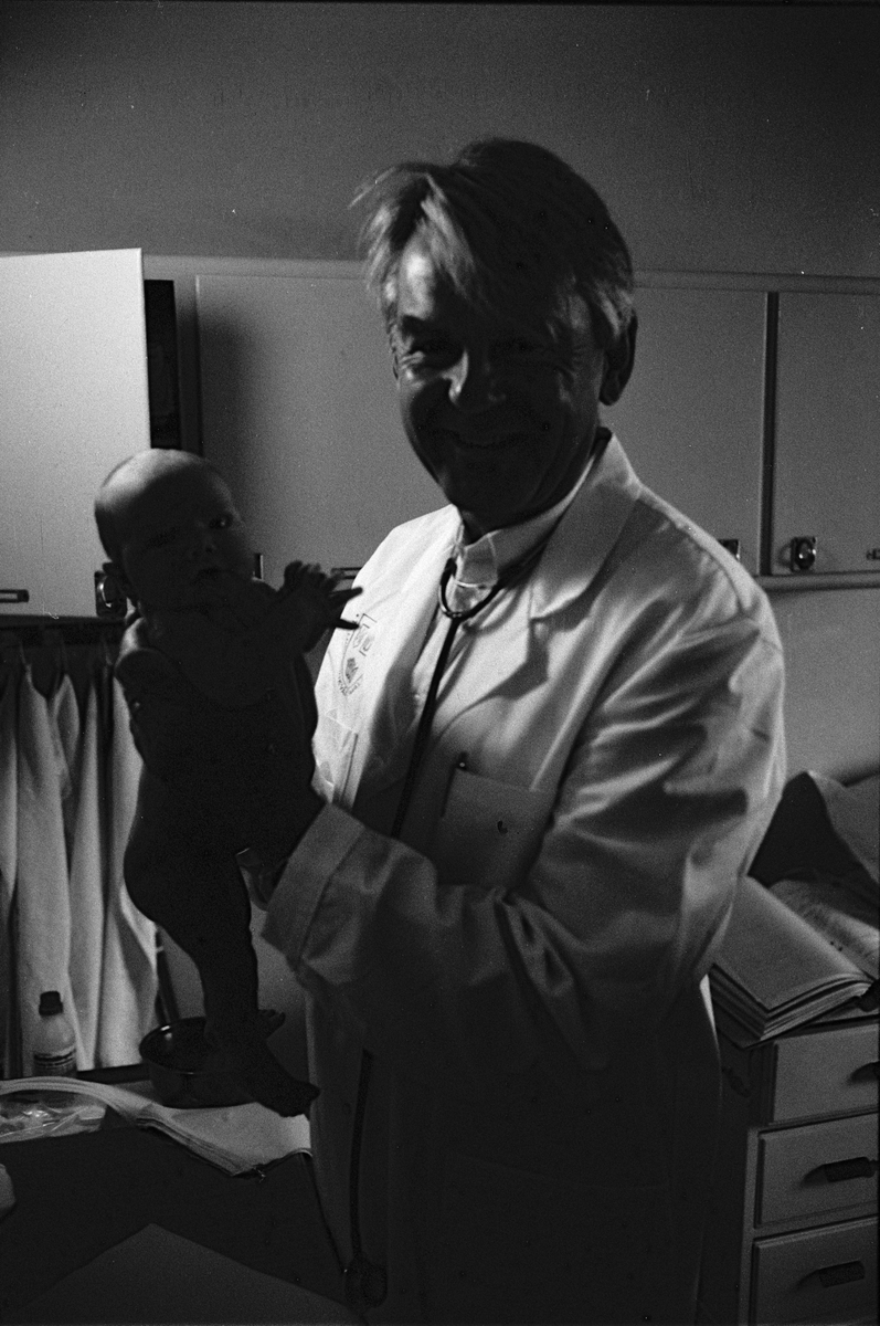Professor Yngve Hofvander med ett spädbarn, lättvårdsavdelningen Ringblomman, Gillbergska barnhemmet, Sysslomansgatan 37 - 39, Uppsala 1986