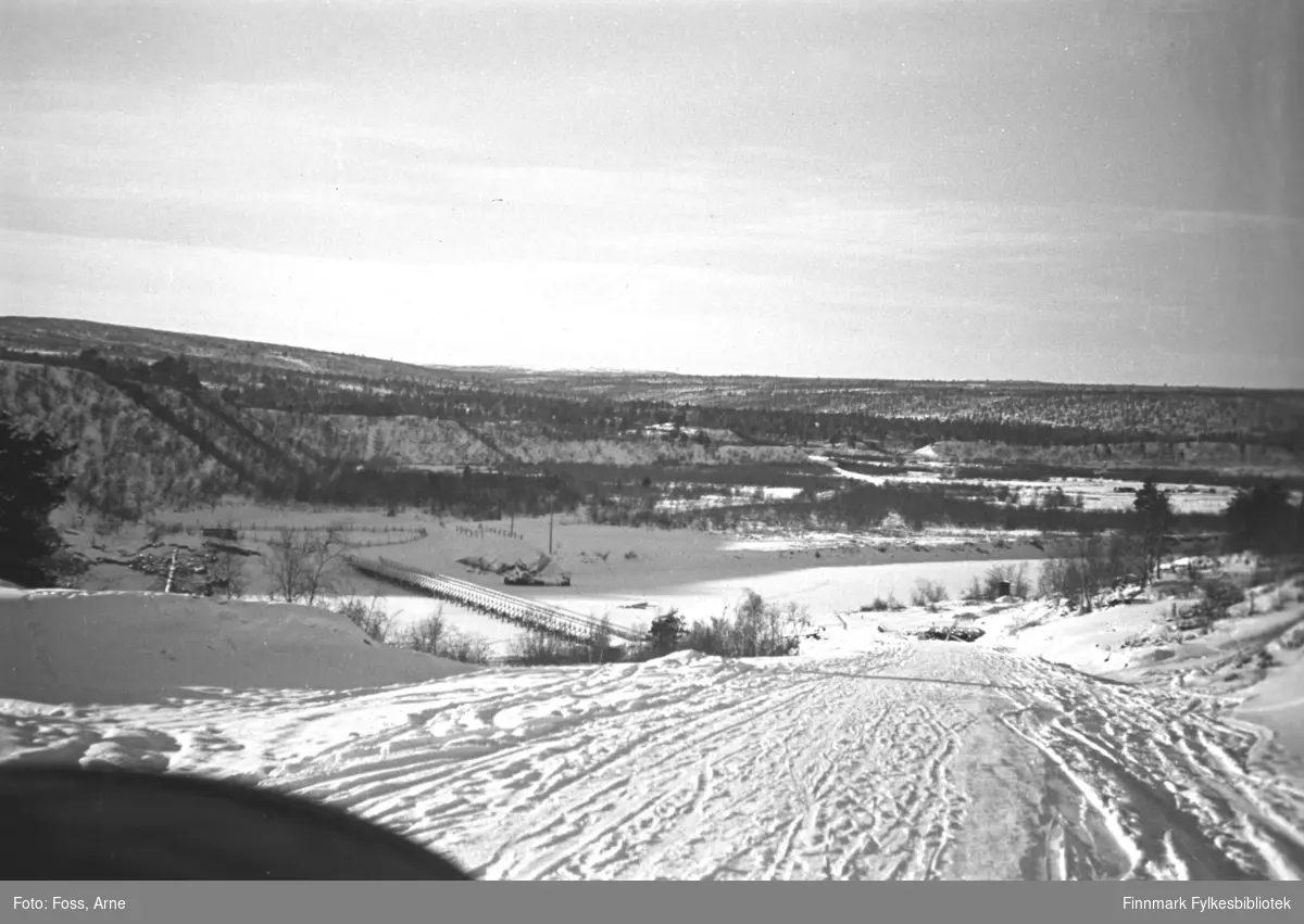 Bilen kjører langs veien i Karigasniemi ved grensen til Norge (i Utsjok kommune i Finland) mot brua og Karasjok kommune, februar-mars 1947. Anarjohka er en grenselv mellom Finland og Norge.