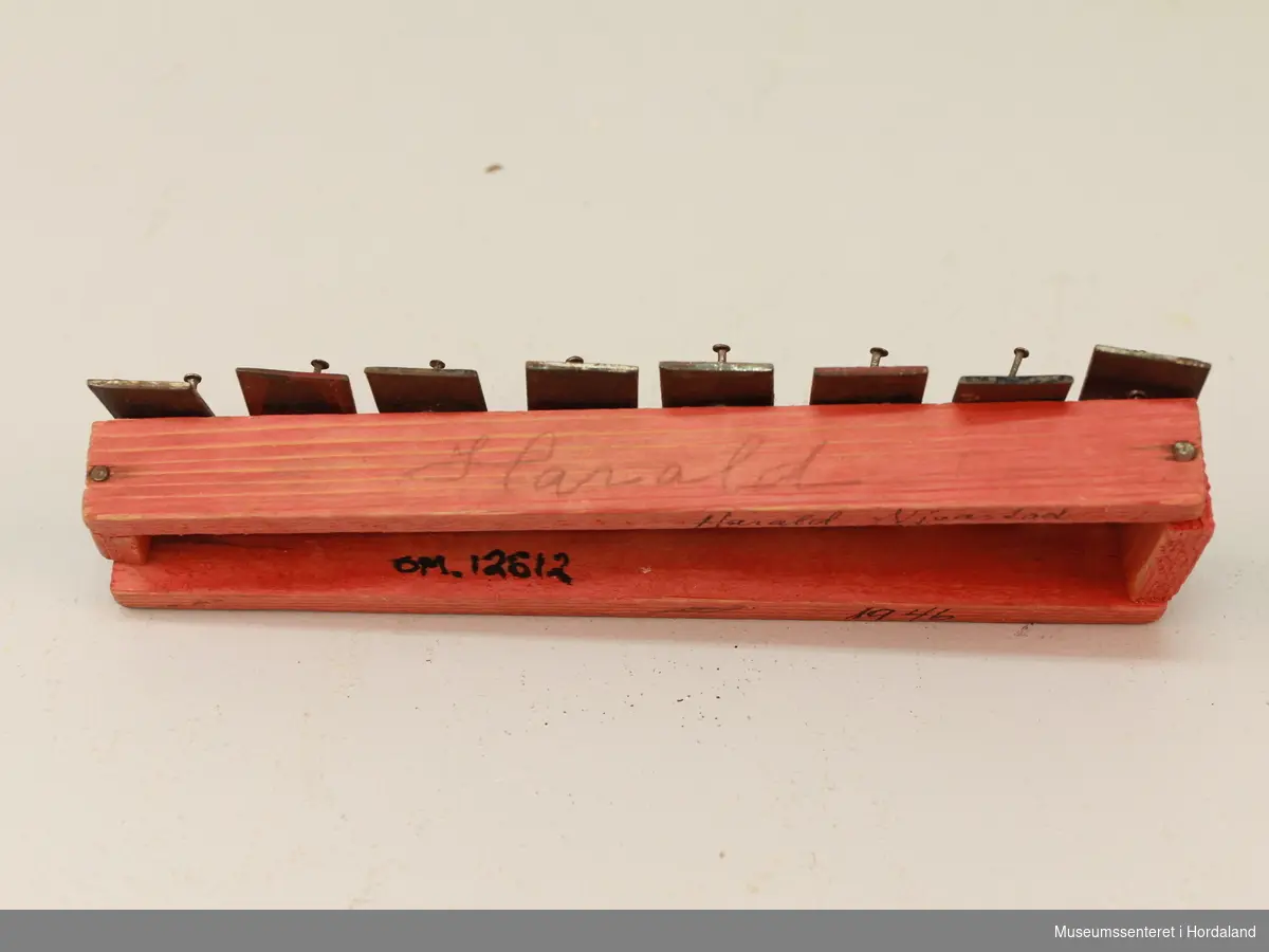 Liten handsnikra xylofon i farga tre med åtte metallstavar. 16 spikrar (2 for kvar stav). Påskrift på sida: "Harald". Påskrift under: "Harald Njåstad 1946".