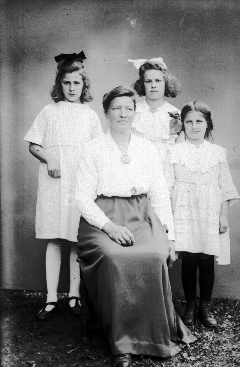 Kvinne med tre barn, i protokollen nevnt som 'Fredrikke Anderslien eller Anderssen Nymo med wienerbarn. Johanne Ripka til venstre'