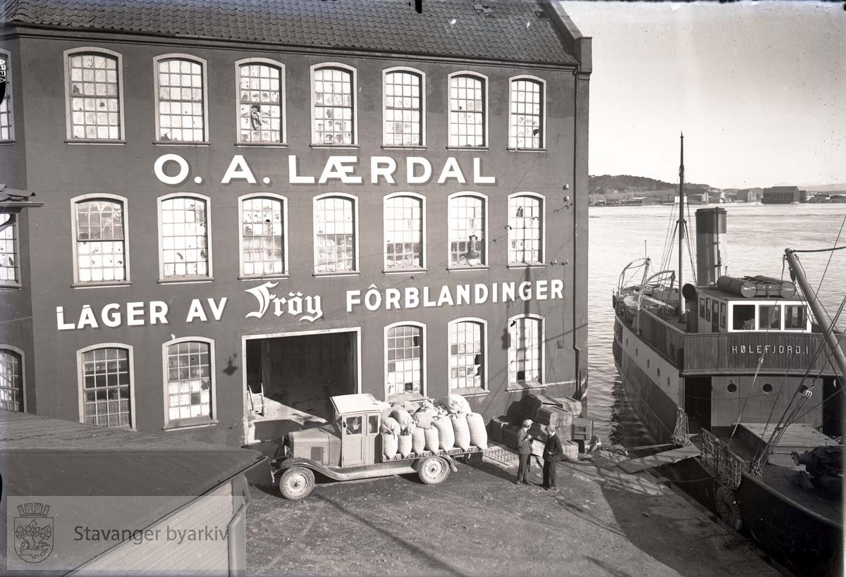 Lageret til Frøy Forblandinger..Hølefjord liggende til kai...Frøy AS var eid av A.O. Lærdal og Sønn A.S som holdt til i Nedre Holmegate 26. inneholdt butikk, kontor og en leilighet, i tillegg et sjøhus med noe lager og laboratorie og pakkeavdeling for prosjonsposen til frø....