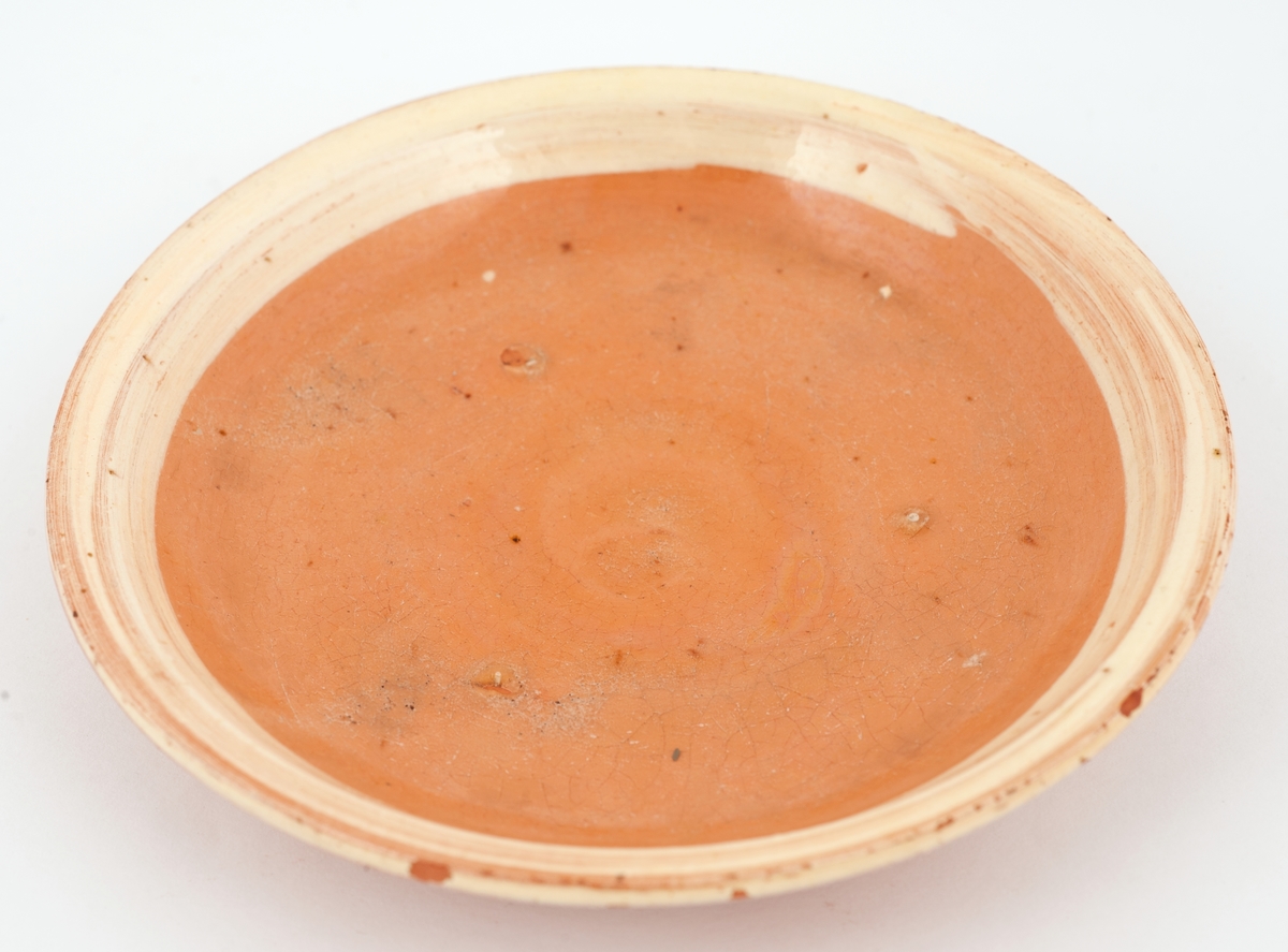 Brun keramikkskål med gulhvit, malt kant.