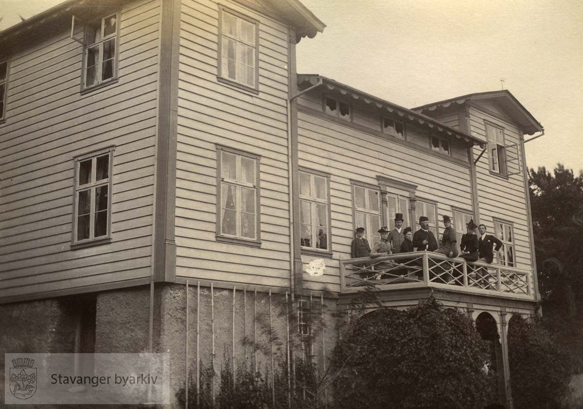 Landsted på østsiden av Ramsvik i Hetlandsmarken. Bygningen på bildet ble oppført av skipper Knud Helliesen. Senere overtok agent Christian Ruus eiendommen. Han står med langpipe i midten på verandaen. Helt til høyre Cornelius Middelthon (1869-1934) som senere kom til å kjøpe Ramsvig og bygge våningshuset helt om.