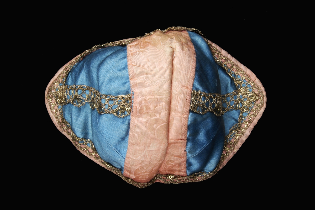 Håndsydd dåpslue. Det blå stoffet var henta frå Berta sin eigen brurekjole som ho bruka då ho gifta seg med Ivar Bjerga i 1821.