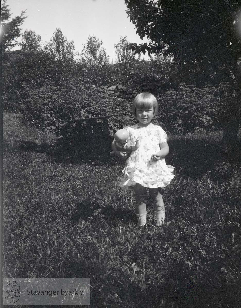 Jente foran busker i hagen
