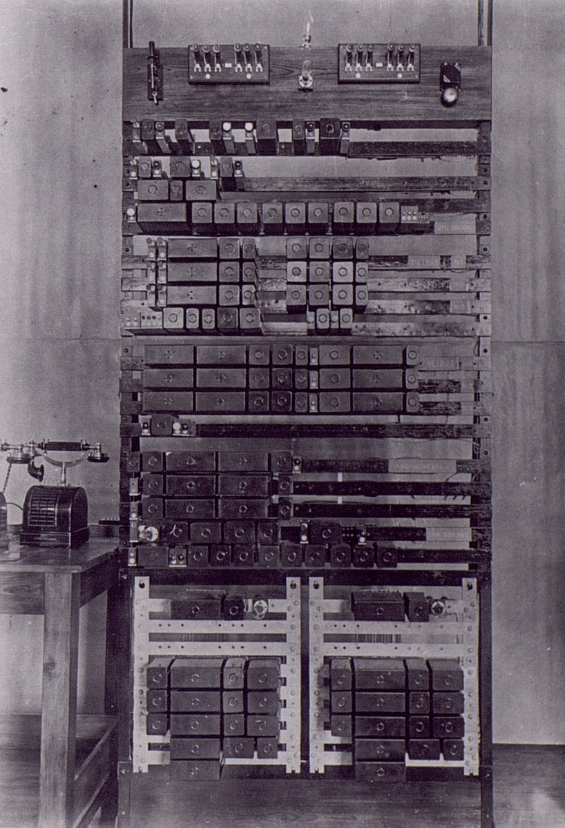 Nya AB Autotelefon Betulander Stockholm (Liljeholmen) april 1915. Provanläggning för mellanledningssystem (reläväxel), uppbyggd som förslag till automatisering av Stockholms telefonnät. (Stativ för understation).