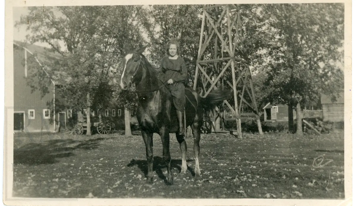 Ung kvinne sitter på en hest