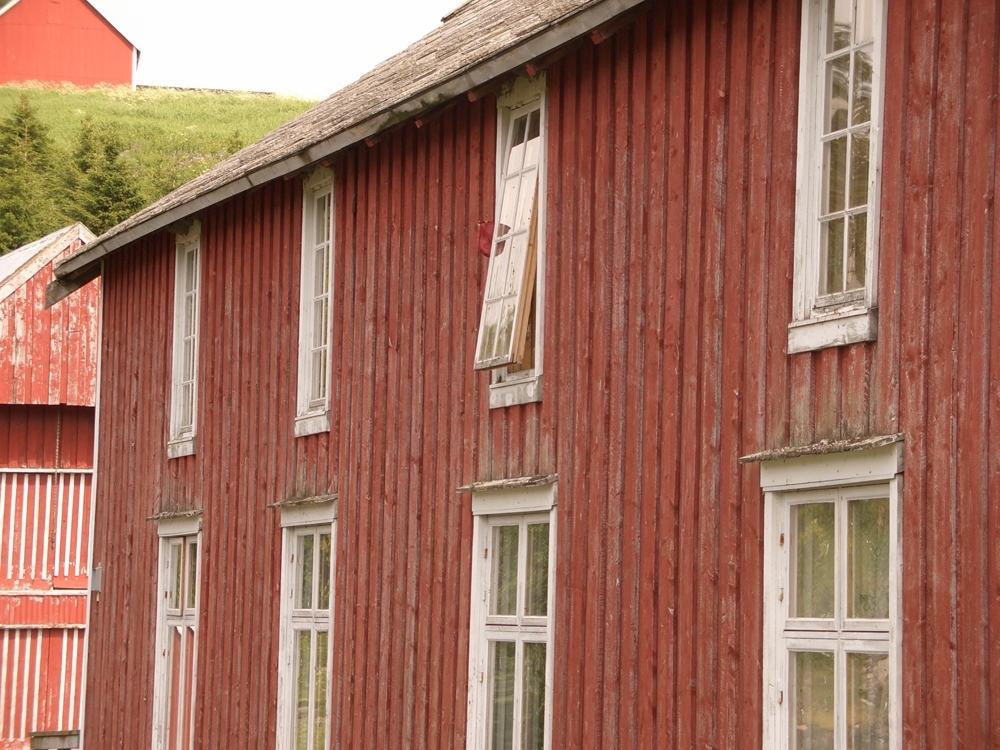 Leirfjord, Bardal, Wangbrygga. Langsiden på brygga med mange vinduer. Veggen og vinduene trener skraping og maling.