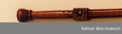 KLM 1652. Runstav. L 97,5+19 cm. Åttkantig med handtag såsom ett svärdfäste, utskuren fyrkantig knapp mellan detta och staven, doppsko av järn. Handtaget med flera initialer: PSRISF:K:I.