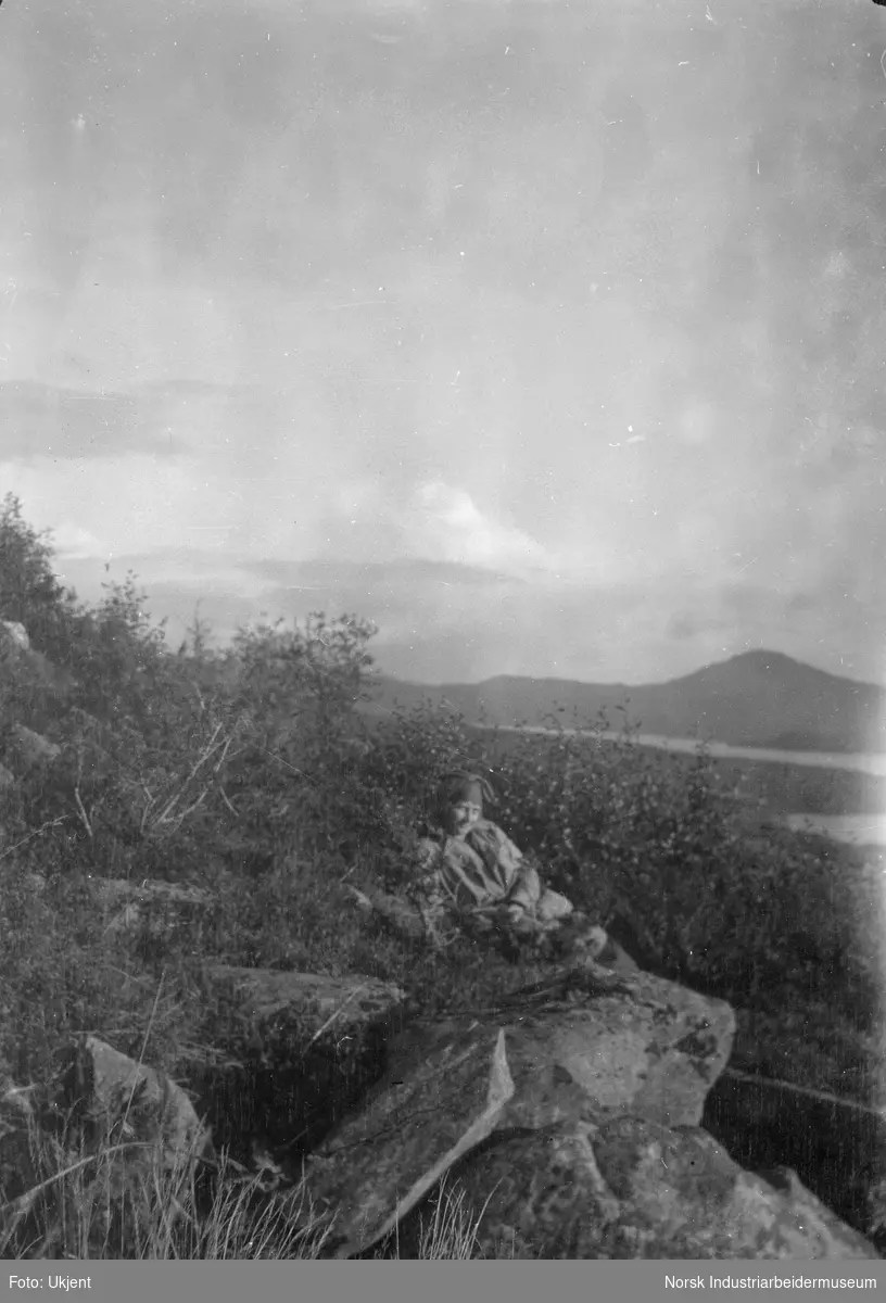 Jente ligger på en stein i naturen
