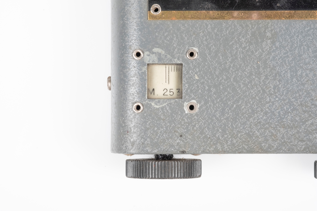 En kortbølgeradio med ytterplater av metall som er lakkert i grått. Radioen har to svarte vriknapper. Det er et lite vindu ved den ene vriknappen som viser frekvensen. På baksiden er det ledning som kobles til batteriet. Det er to hull til plugger og en kontakt for øreproppene. Det er påfestet en plate med instrukser på på oversiden. Mellom vriknappene er det påfestet en liten plate med modellnummer.