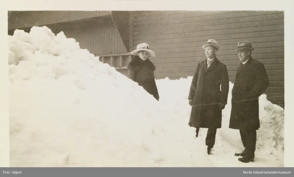 To menn og en kvinne står mellom to snøhauger