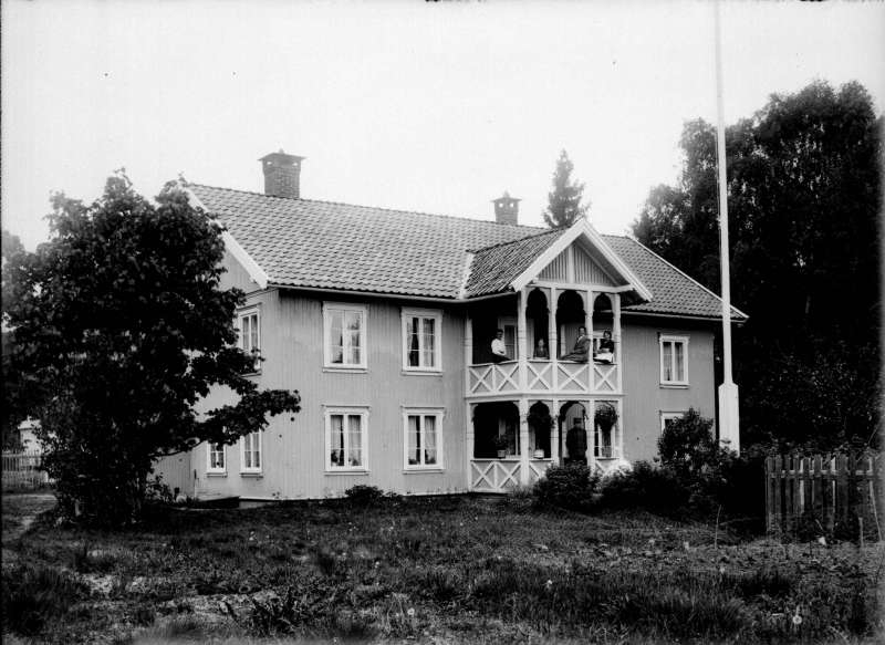 Toetasjes hus med folk på verandaen. - Maihaugen / DigitaltMuseum