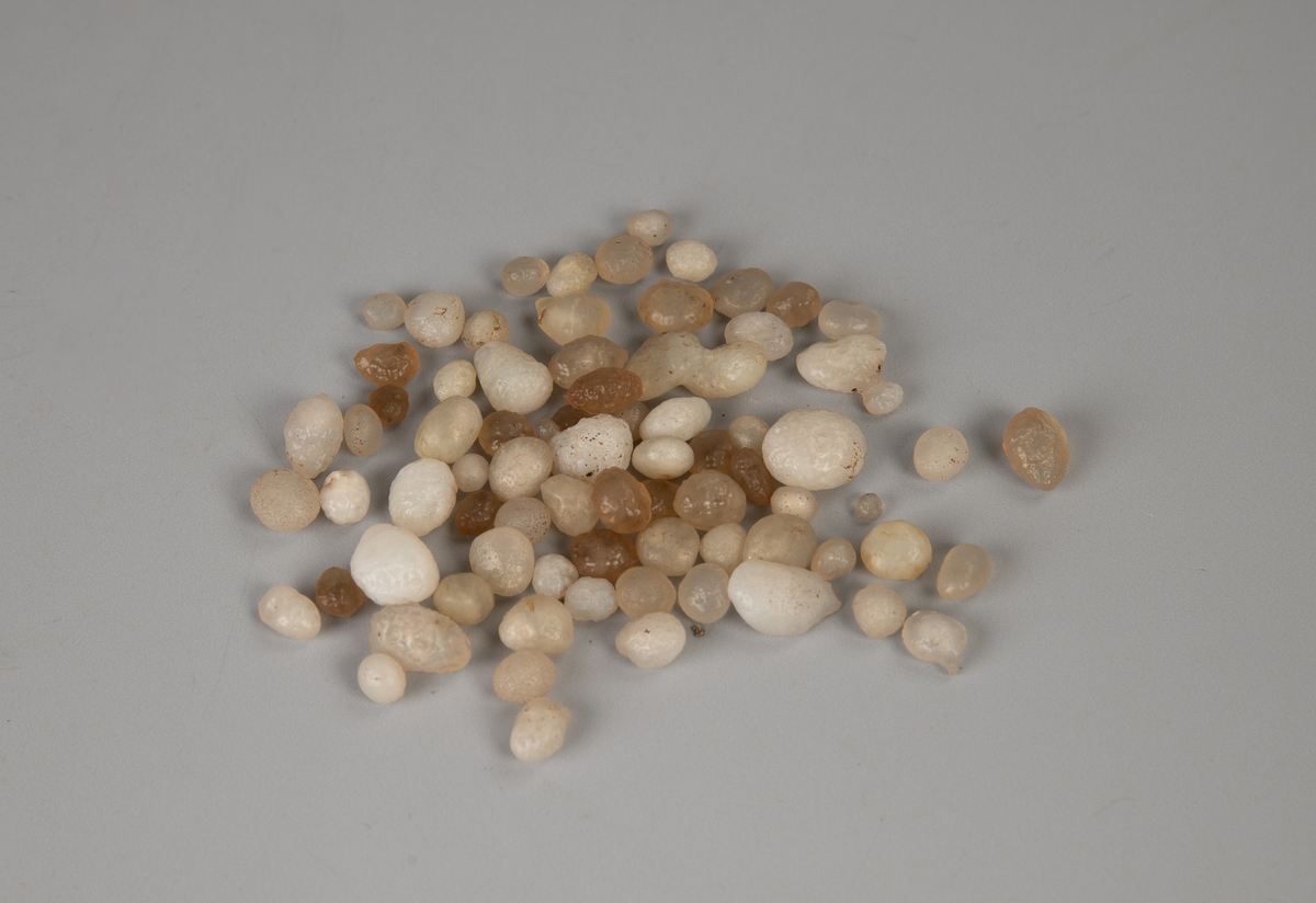 61 små hvite, glattskurte stener, de fleste  som perler. Noen litt større steiner og 15 av  samme sort, men svakt brunlige.