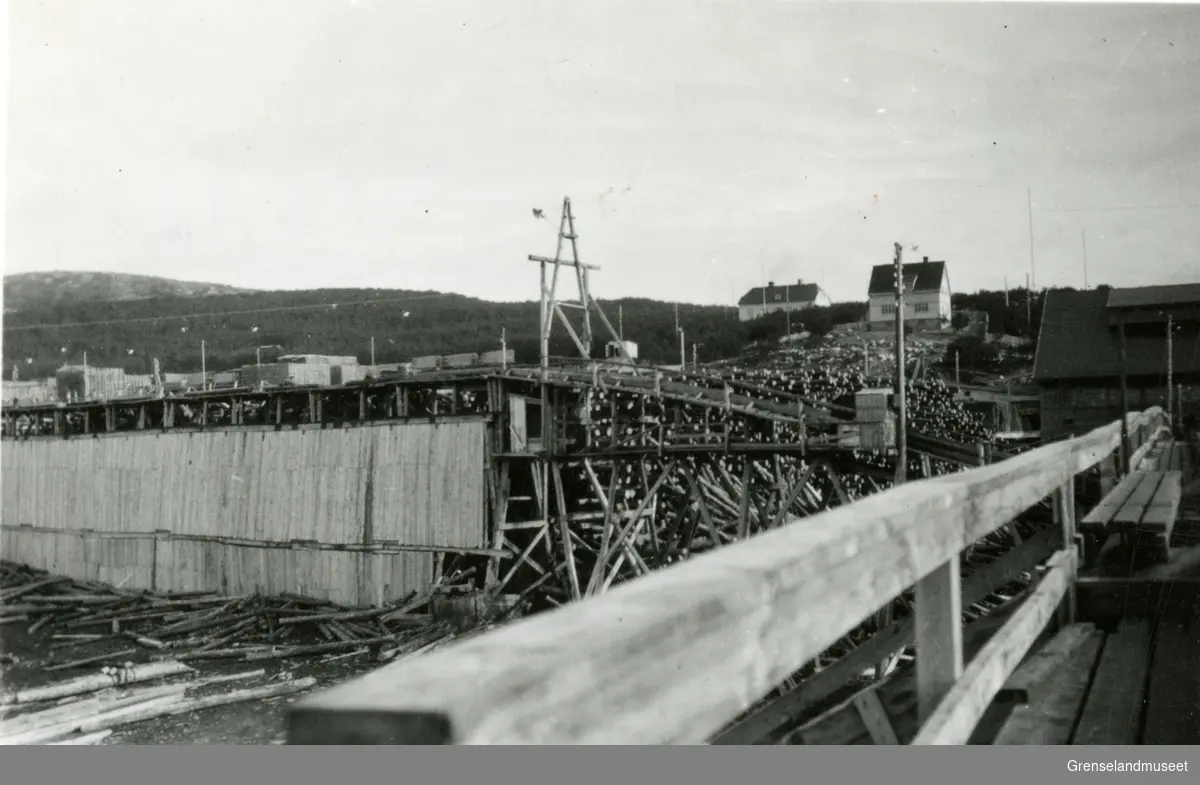 Motiv fra sagbruket på Jakobsnes før 1940. Tømmer og utebelysning sentralt i bildet. I bakgrunnen til venstre sees plankestabler, mot høyre ligger kontorbygg og disponentbolig.