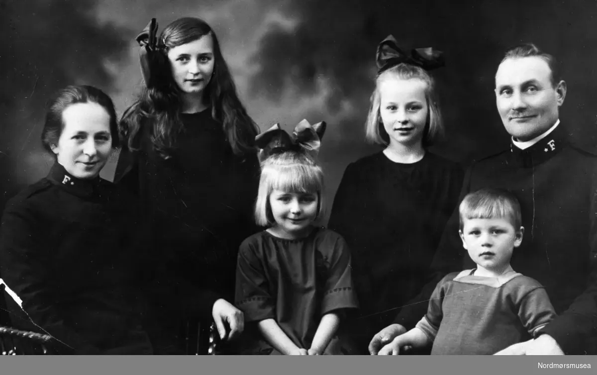Familiefoto på postkort., hvor foreldrene er i ført Frelsesarmeens uniform. Muligens fra Kristiansund. Fotograf er ukjent. Fra Nordmøre museums fotosamlinger.