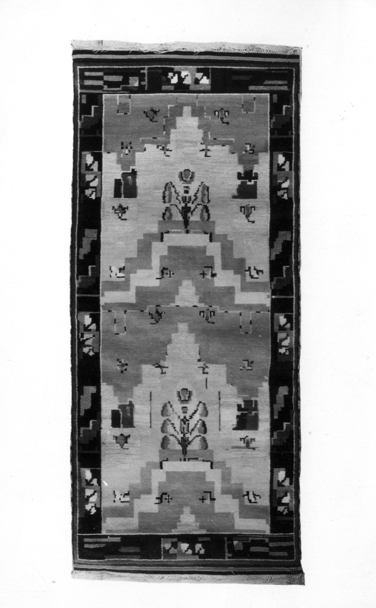 Foto (svart/vitt) av en flossamatta med motiv av stiliserade blommor m.m.

Inskrivet i huvudbok 1983.