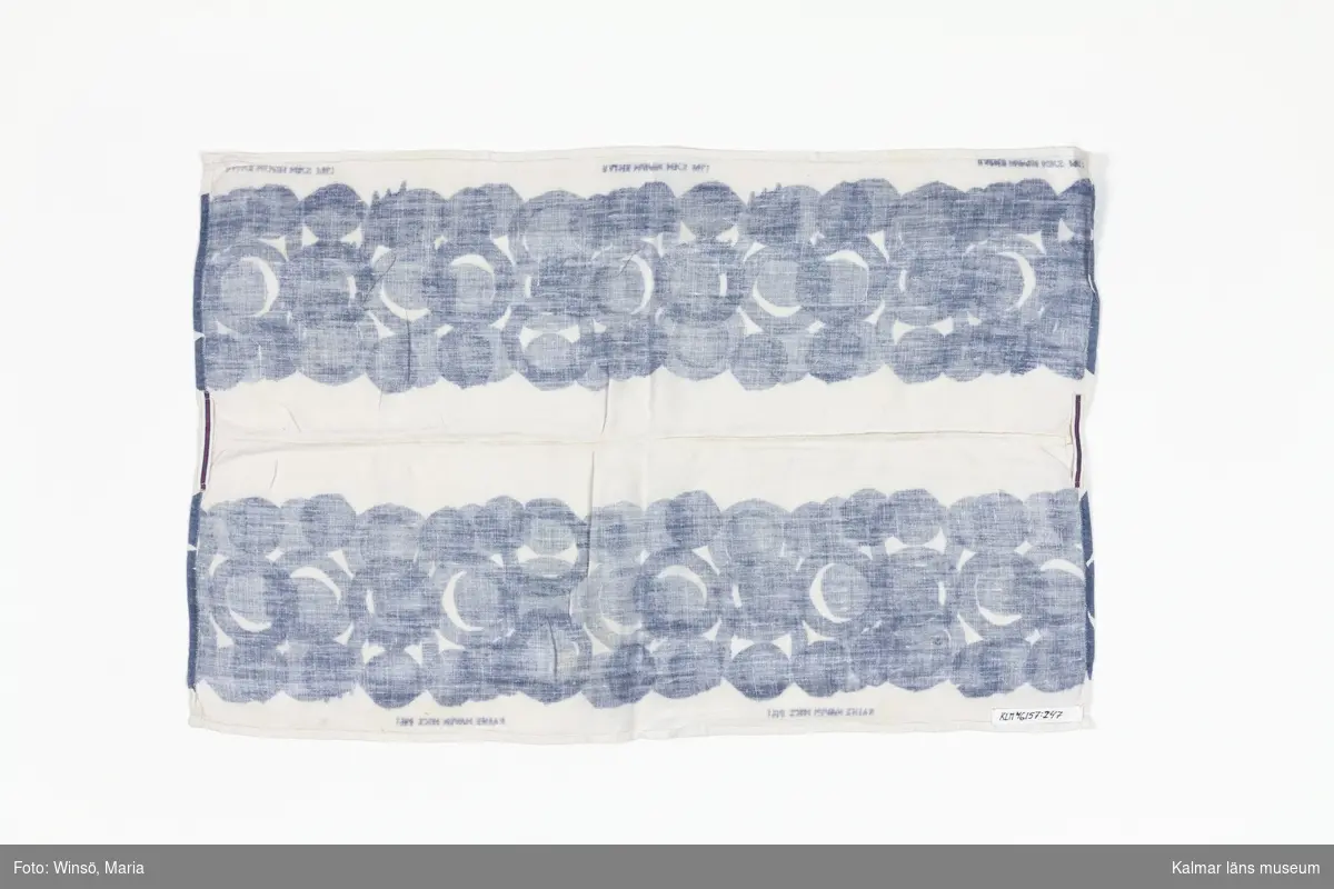 KLM 46157:247. Handduk, kökshandduk, med tryck, textil. Handduk i vitt linnetyg, bestående av två ihopsydda tygdelar med tryckt mönster i ljusblå färg. Två fastsydda bomullsband, ett i mitten på varje kortsida, med rand i blått och rosa. Tryckt text i blått på fem ställen: RAINE NAVIN HKS 1961.