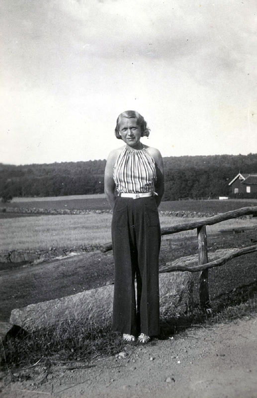 Inga Lill Dahlberg Börjesson från Burås i Göteborg (1915 - 2002) står på en landsväg i Tulebo. Sommargäst hos Fredrikssons och Nilssons.
Till höger skymtar uthusen (sommarbostäder) hos Oskar Fredriksson.