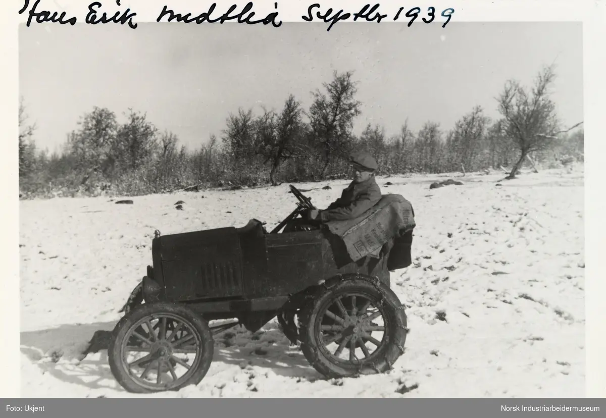 Hans Erik Midtlia, Sundet, Møsstrond. Mann med sikspens sitter i et åpent kjøretøy i et snødekt landskap. Kjøretøyet har kjetting på bakhjulene. en ombygd, forkortet Ford T 1920-24