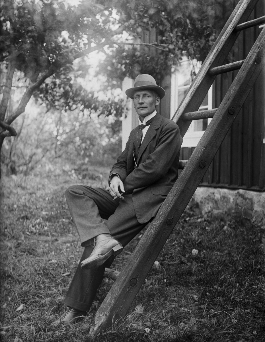 "Helge Pettersson Kråktjärn, Broddbo ensam på stegen", i trädgården i Sävasta, Altuna socken, Uppland 1921