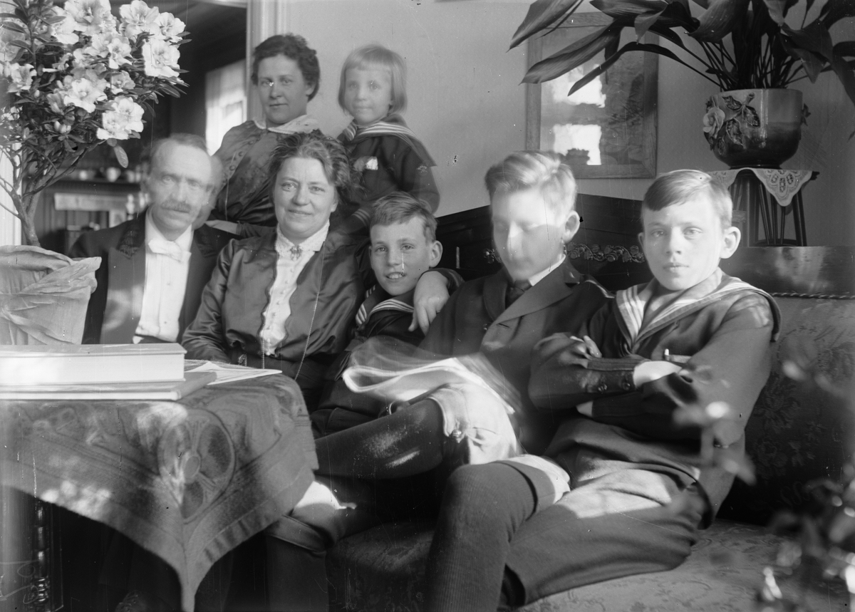 Christiane och Ruben Liljefors, med barnen Roland, Alf, Ingemar och Marit, och en kvinna, sittande i soffan i hemmet i Gävle cirka 1920-tal