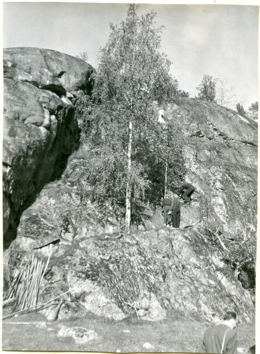 Kung Karl sn, Kungsör.
Kungsör Hembygdsförenings fornminnesutfärd den 1 juni 1957.
Tre personer klättrar uppför bergvägg.