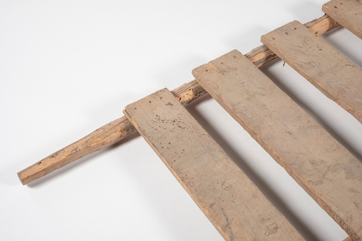 Rektangulær båre, brukt til å bære slaktegris. Består av 8 planker lagt på tvers og spikret fast til to trestenger. Det er rester av bark på stengene, og endene som er håndtak er spikket til for bedre grep.