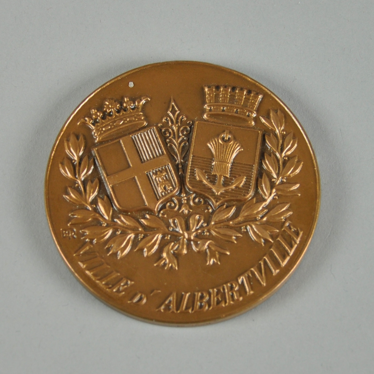 Bronsefarget medalje med motiv av to våpenskjold og det som ser ut til å være en olivenkrans. Med medaljen følger det en boks. Ligger i en rød eske av kartong med rødt fløyelsfôr og hvitt silkefôr.