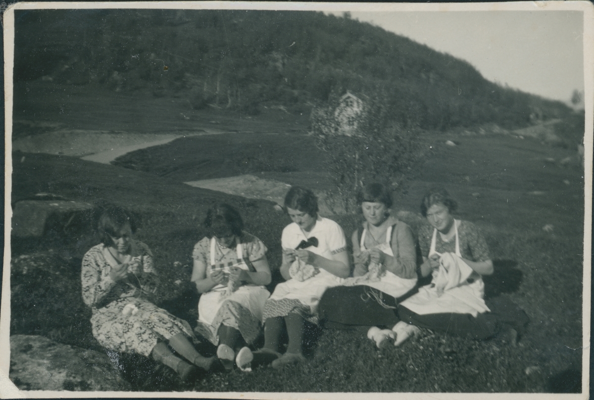 Fire kvinner sitter utendørs med håndarbeide.