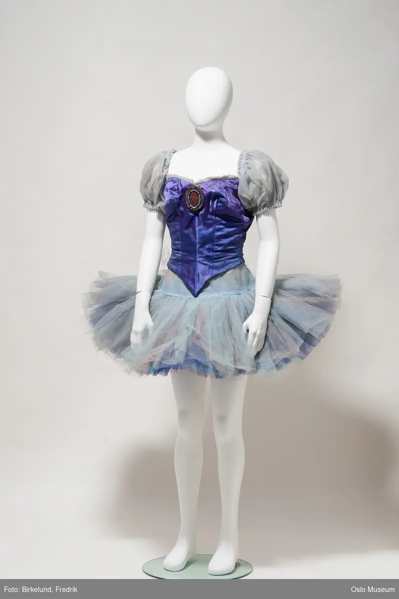 Kjole, ballettkjole i lyseblå tyll med fiolett silkeliv, puffermer i tyll, lukkes i rygg med hekter