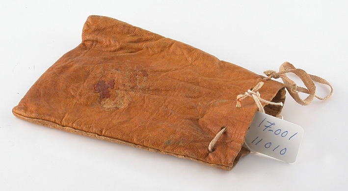 Av ljusbrunt läder med dragsko av skärt bomullsband på framsidan skrivet med tusch, på baksidan en bit lack efter sigill.

Mått: Br. nedtill 95 mm, br. upptill 75 mm.