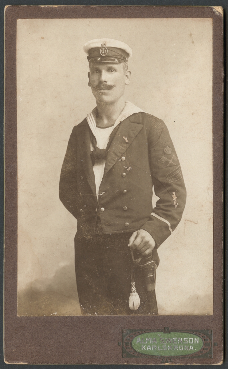 Denna visitkort visar ett porträtt av Carl Svensson som ung man. Denna knästycke avbildar honom som underofficerskorporal i uniformen av Svenska flottan med yrkesbeteckning för signalmatroser. Hans höger arm vilar på en huggare med portepé.