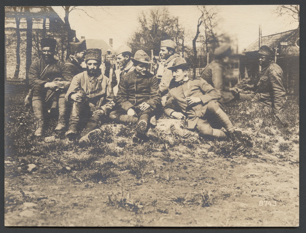 Bilden visar  krigsfångar från olika länder med olika hudfärger som sitter på marken och samtalar. Arabiska, svarta och vita soldater speglar sammansättningen av de allierade styrkor.