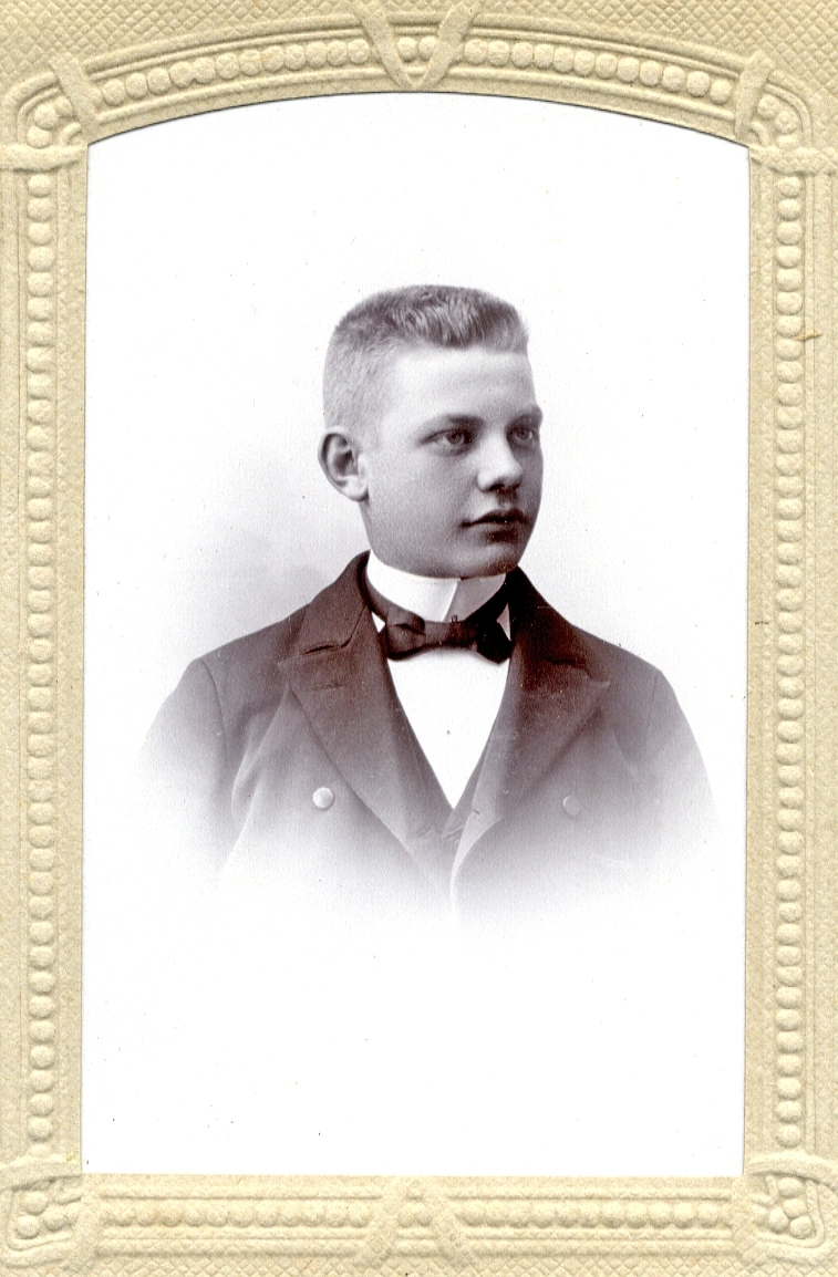 Foto av en ung man (tonåring) klädd i kavaj med väst, stärkkrage och fluga. Bakpå fotot står antecknat: "G. Lönn 1902". 
Bröstbild, halvprofil. Ateljéfoto.