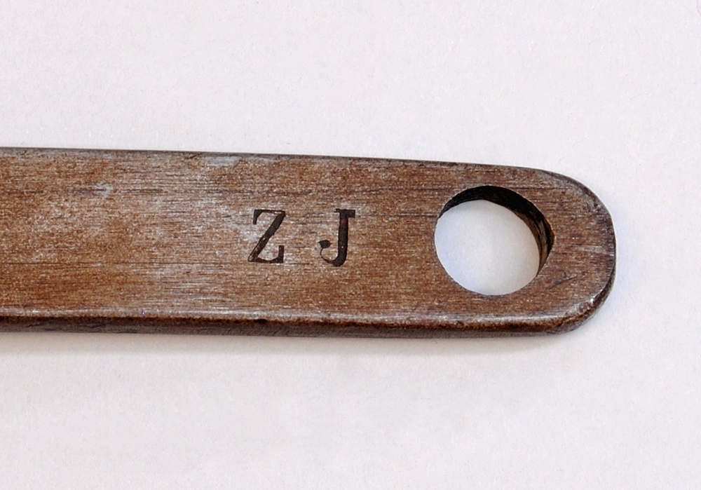 Skiftnyckel av silvergrå metall med rostfläckar. Skiftnyckelns huvud består av två rörliga delar som rör på sig genom att användaren snurrar på en skruv som sitter strax nedanför de två rörliga delarna. På sidan av skruven finns texten: "S T" präglad. 

Längst ned på skiftnyckelns skaft finns ett cirkelformat hål. På ena sidan av skaftet finns texten: "S J" präglad. På den andra sidan av skaftet finns texten: "Z .J" präglad.