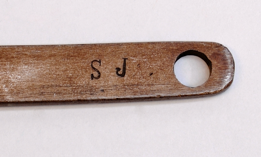 Skiftnyckel av silvergrå metall med rostfläckar. Skiftnyckelns huvud består av två rörliga delar som rör på sig genom att användaren snurrar på en skruv som sitter strax nedanför de två rörliga delarna. På sidan av skruven finns texten: "S T" präglad. 

Längst ned på skiftnyckelns skaft finns ett cirkelformat hål. På ena sidan av skaftet finns texten: "S J" präglad. På den andra sidan av skaftet finns texten: "Z .J" präglad.