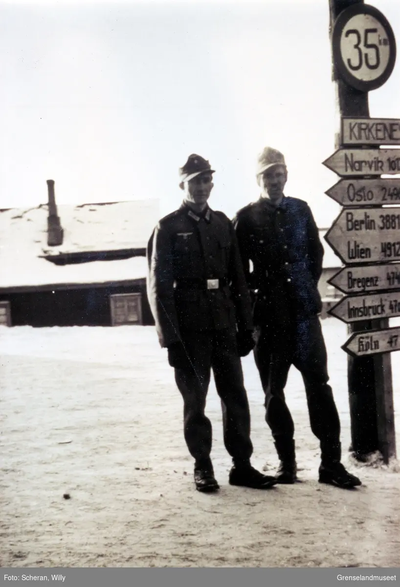 To tyske soldater poserer ved veiviseren på Lønboms Plass ved kaia i Kirkenes. 