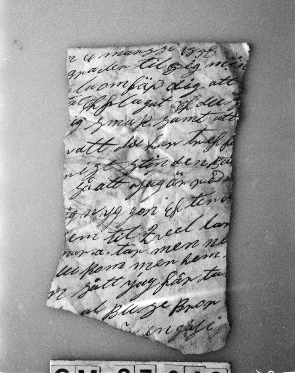 Papper.
Del av pappersark. Lumppapper.
Skrivet med sepiabläck. Text på bägge sidor. Ena sidan: Ur brev från 4 mars 1858.
Andra sidan: Ofvansjö Storvik osv.