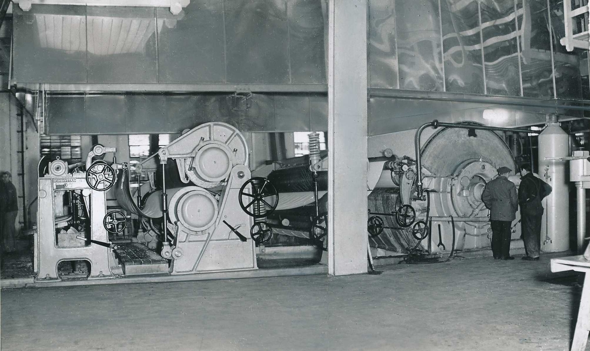 To menn ved oppfangermaskinen i produksjonssalen i det gamle tresliperiet