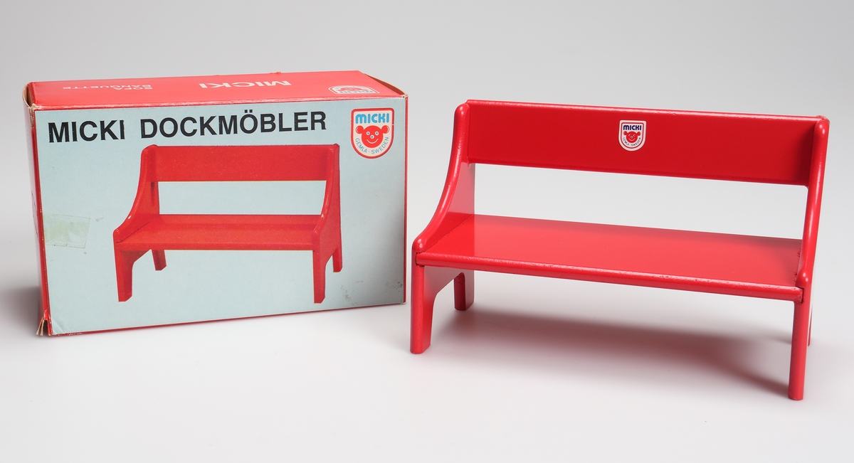 Rödlackerad soffa (dockmöbel) tillverkad av träfiberskiva. Soffan är förpackat i en röd och vit pappkartong med text på svenska, tyska, engelska och franska.

Inskrivet i huvudkatalog 1982.