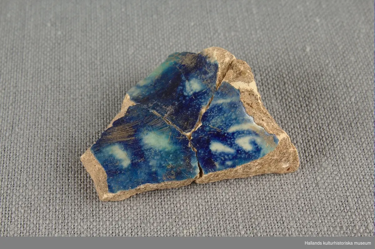 Skärva av drejat och glaserat lergods. Glaserat i blått och vitt. 

Ihoplimmad med föremålen vmf018747 och vmf018735.