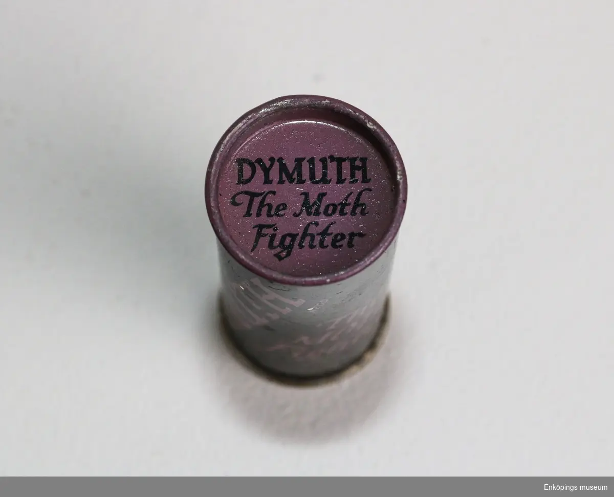 Svart oval metallburk med text i lila färg: "DYMUTH The Moth Fighter". Äldre insektsmedel mot mal.