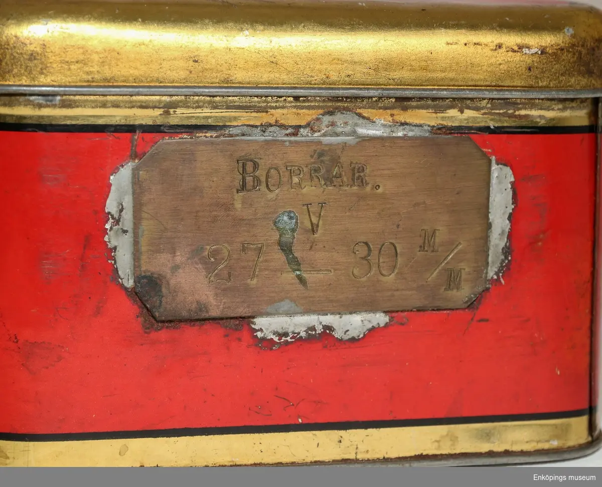 Röd plåtlåda för verktyg med texten: "PRIMUS REG. TRADE MARK A/B B. A. HJORTH & CO STOCKHOLM SWEDEN BORRAR V, 27-30 SV. PANT. No 92594, PRI-MUS".