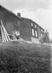 Kvinne og lite barn ute på gårdstunet ved huset på Ner-Ensta