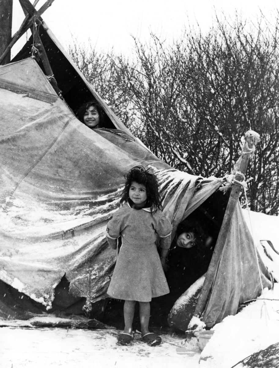 Romska barn i Skurup vintern 1960. Endast ett enkelt tält ska skydda familjen från vind och snö.  Boendestandarden bland svenska romer var under 1900-talets första hälft mycket varierande. Familjer som hade det bättre ställt kunde äga flera tält, medan fattigare familjer enbart hade ett tält. Man sov då där marken var minst lerig.